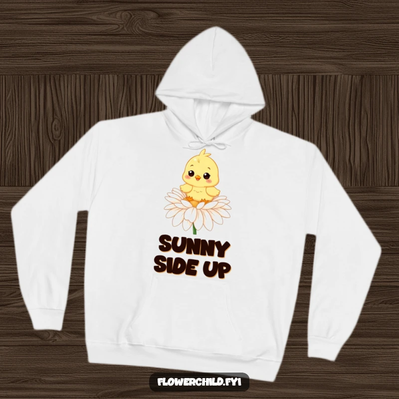 Funny hoodie showcasing a happy chick comfortably settled on a large daisy, perfect for cozy and cheerful vibes.
